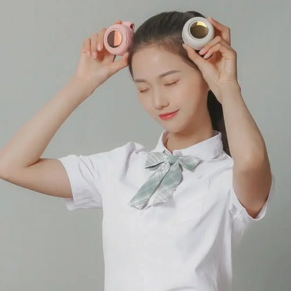 White bladeless fan held in both hands while resting by a person’s face
