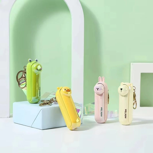 Set of mini handheld keychain fans on display in green, yellow, white, and pink.