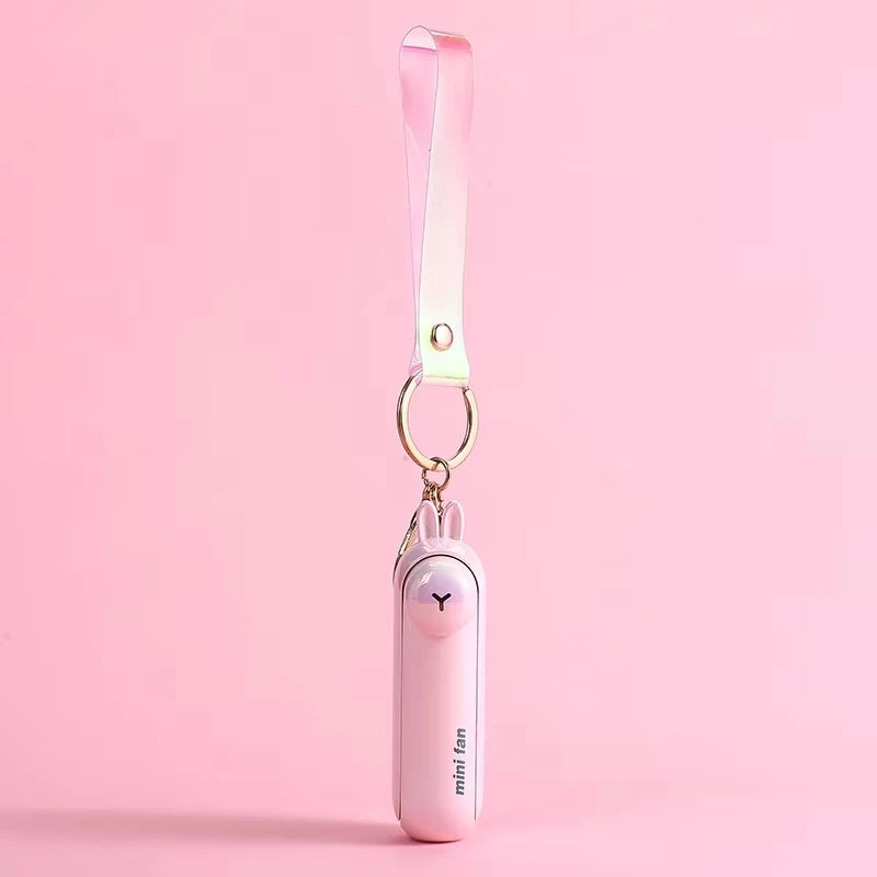 Pink mini handheld keychain fan with ribbon strap and metal key ring, hanging view.