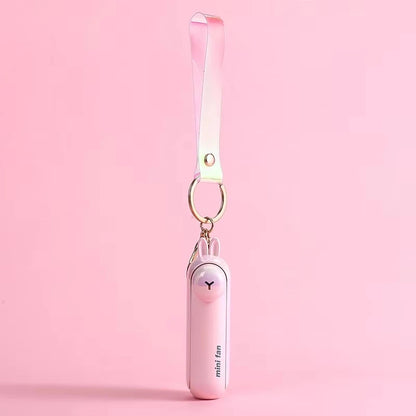 Pink mini handheld keychain fan with ribbon strap and metal key ring, hanging view.