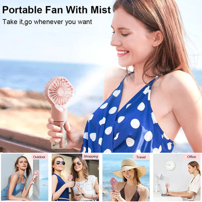 Pink portable mist fan held in hand with fine spray visible from the nozzle