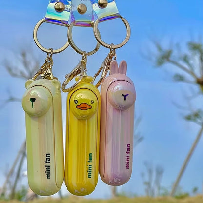 Three mini handheld keychain fans hanging: green, yellow, and pink with metal rings.